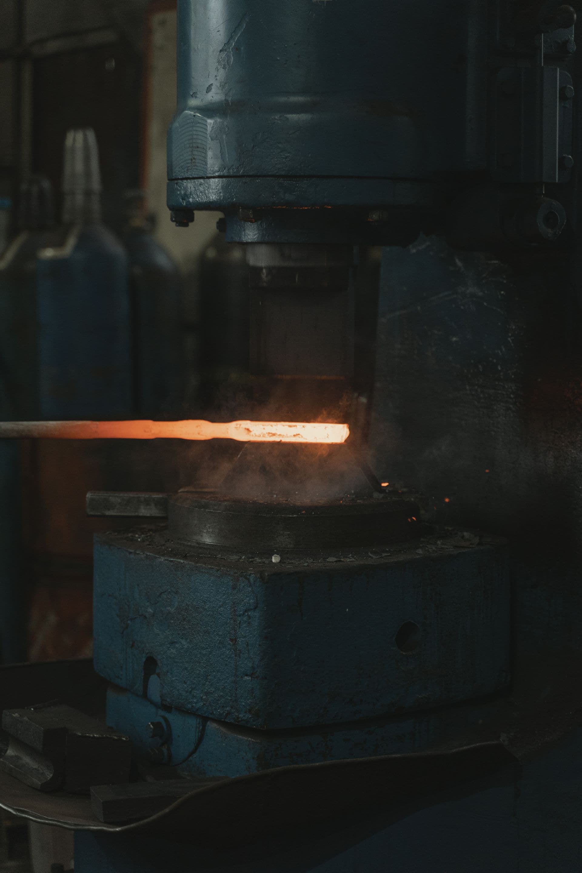 A forging press shaping a glowing steel billet